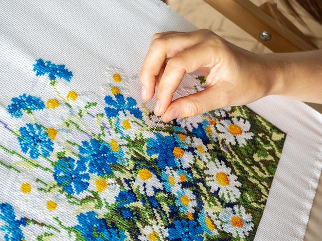 Kobieca ręka haftująca szczegół wzoru